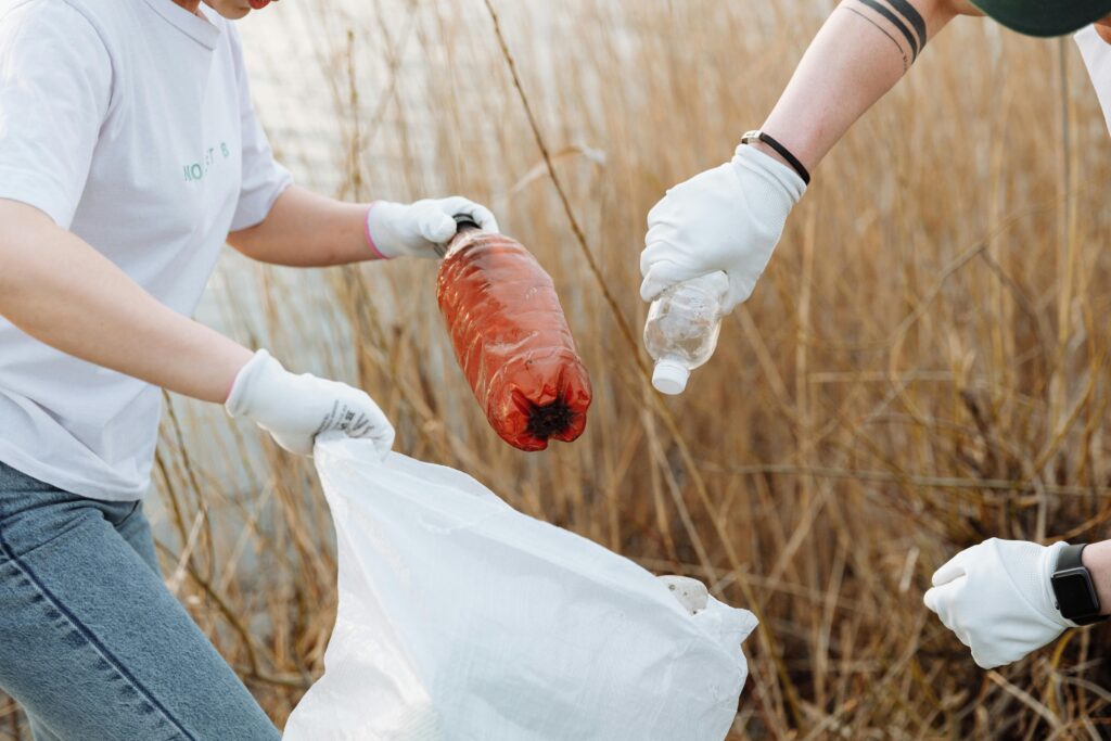 Two volunteers picking up litter outdoors to support environmental conservation.
